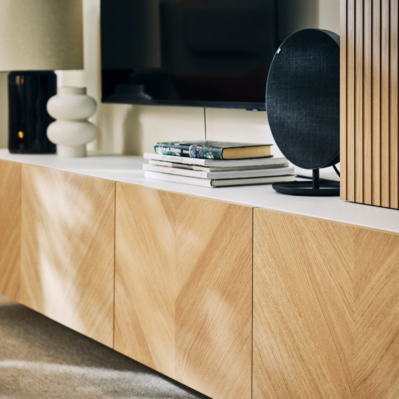 BESTÅ media storage combination with books, decorative objects and a SOLSKYDD Bluetooth speaker.