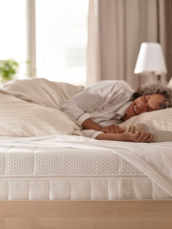 A woman with brown curly lying face down on a pillow sleeping comfortably.