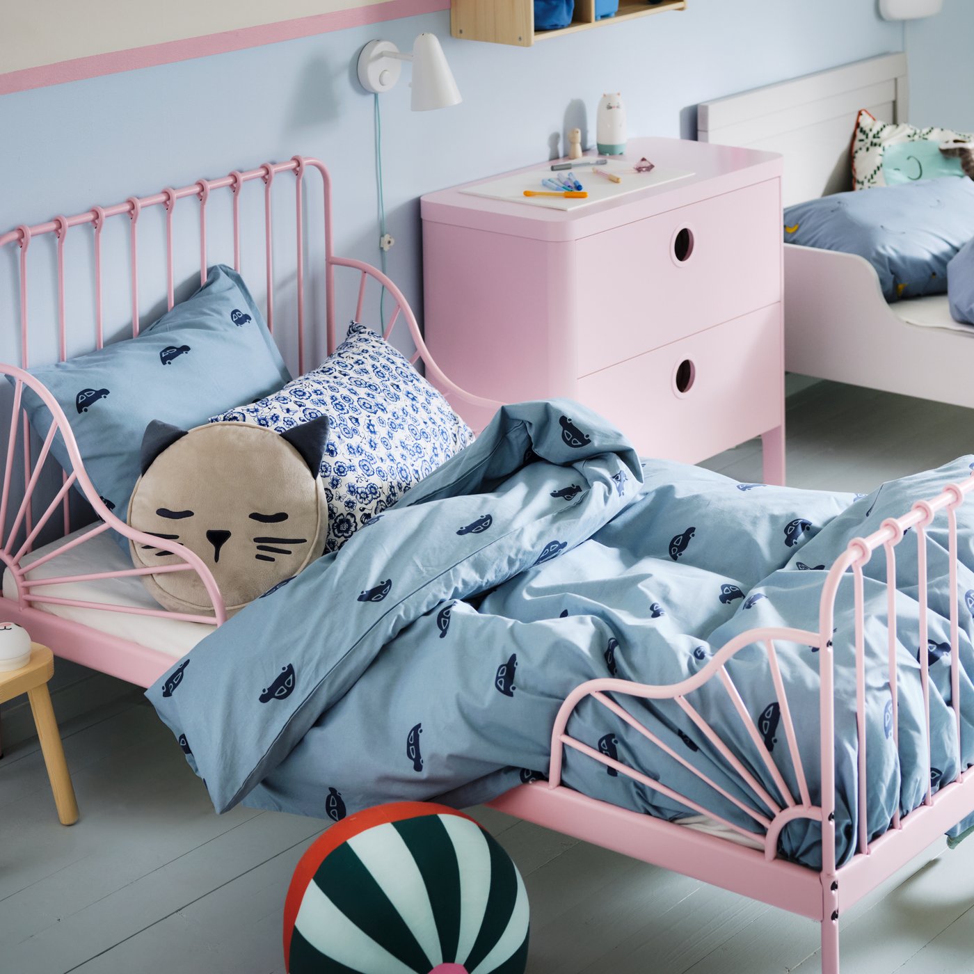 A children's bedroom with a light pink MINNEN extendable bed and a white bed made with blue VÄNKRETS and BARNDRÖM bedding.