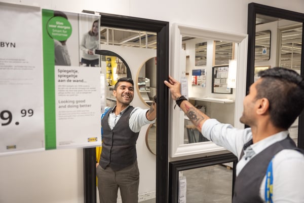 Image 30: A smiling man inside an IKEA store looking at an IKEA mirror.