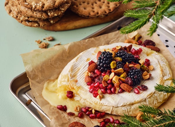 Una teglia con del brie al forno con frutti di bosco e noci tostate