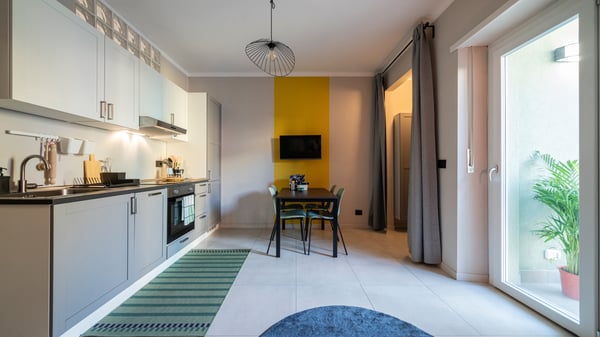 Una vista con un angolo dispensa/lavanderia con scaffale JOSTEIN e la combinazione ENEHT sulla destra.
A sinistra, una cucina/soggiorno con cucina lineare arredata con mobili ENHET, la lavastoviglie e il piano a induzione.
Al centro ci sono un tavolo SANDSBERG, abbinato alle sedie impilabili LIDÅS con sedile sagomato e schienale flessibile.