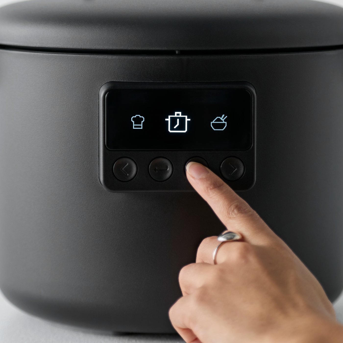 A close-up of a hand selecting settings on a black TILLREDA multicooker navigating the display.