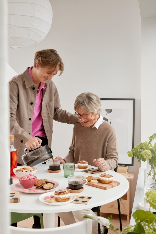 En ung mand skænker kaffe til sin mor. 