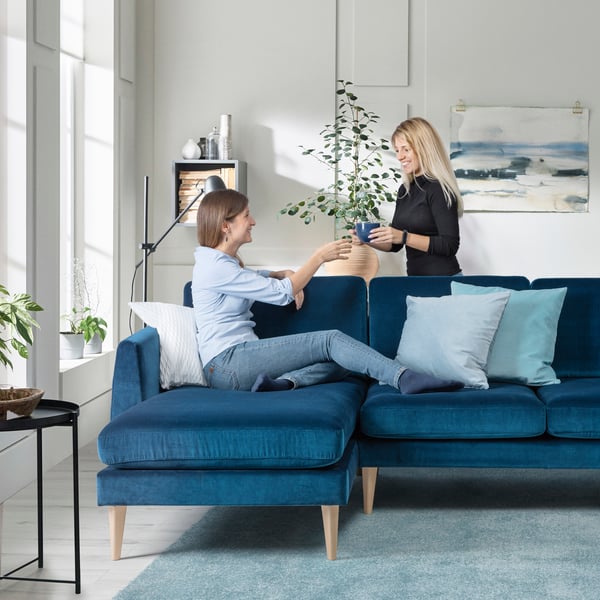 En person halvligger i en blå sammetssoffa med schäslong.