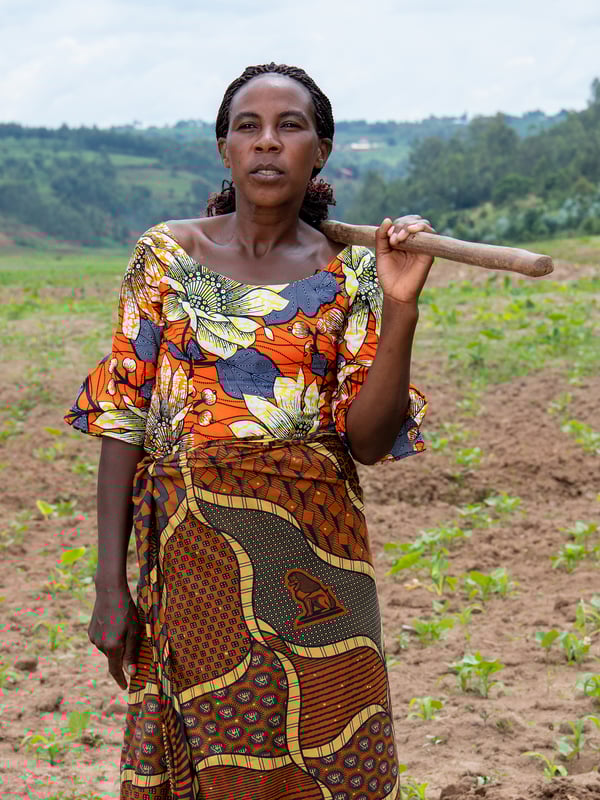 Portrait of Clementine, a Congolese refugee, standing on a field wearing a colorful pattern.