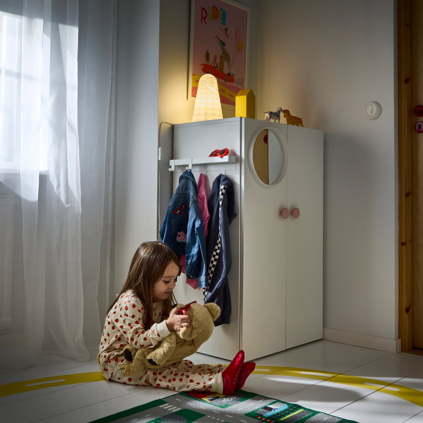 LASTARE wardrobe combination with hanging rail and cabinets placed in a children’s room where a child plays on the floor.
