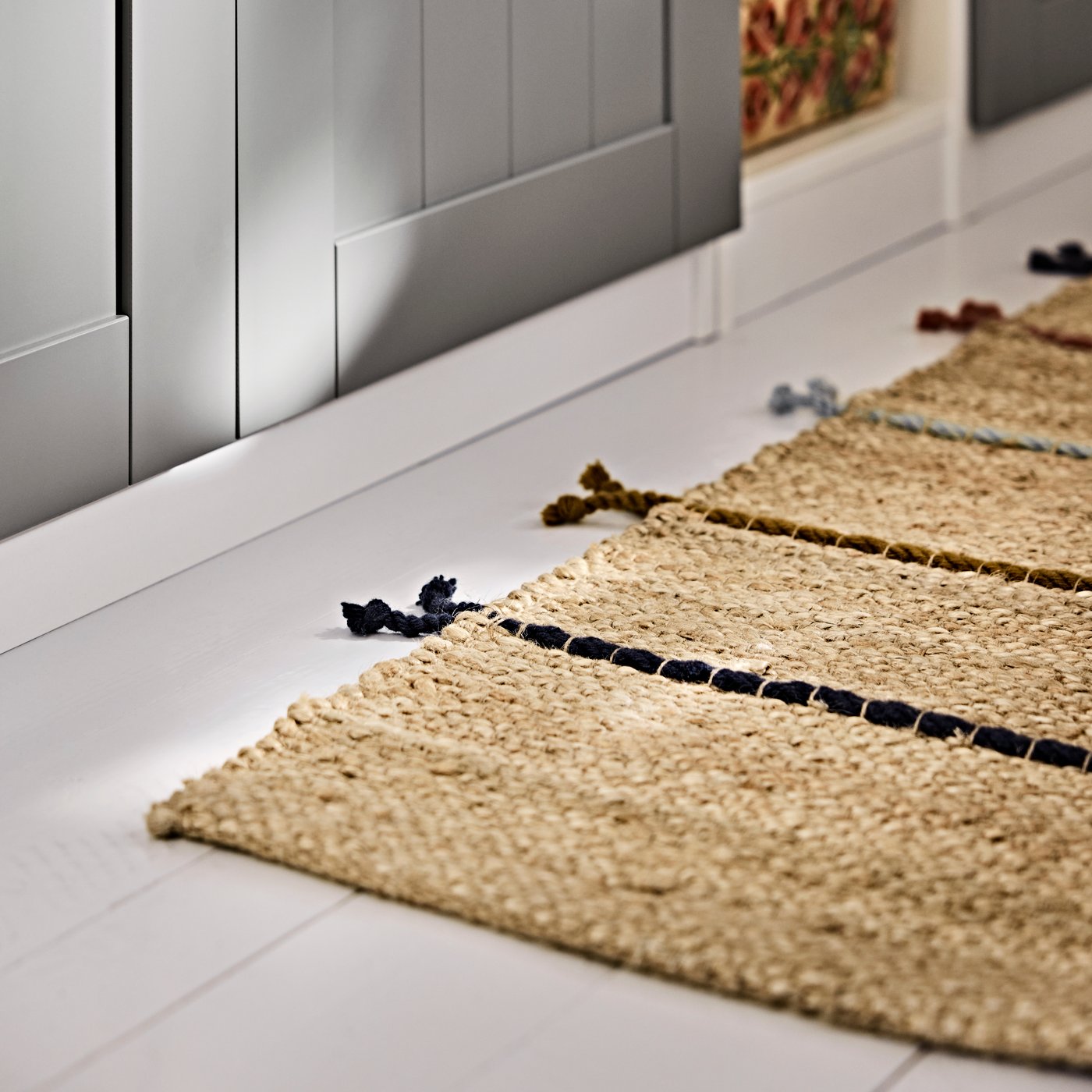 A flatwoven RAKLEV rug running along the wardrobe area, shown with tassel details on the bedroom floor.