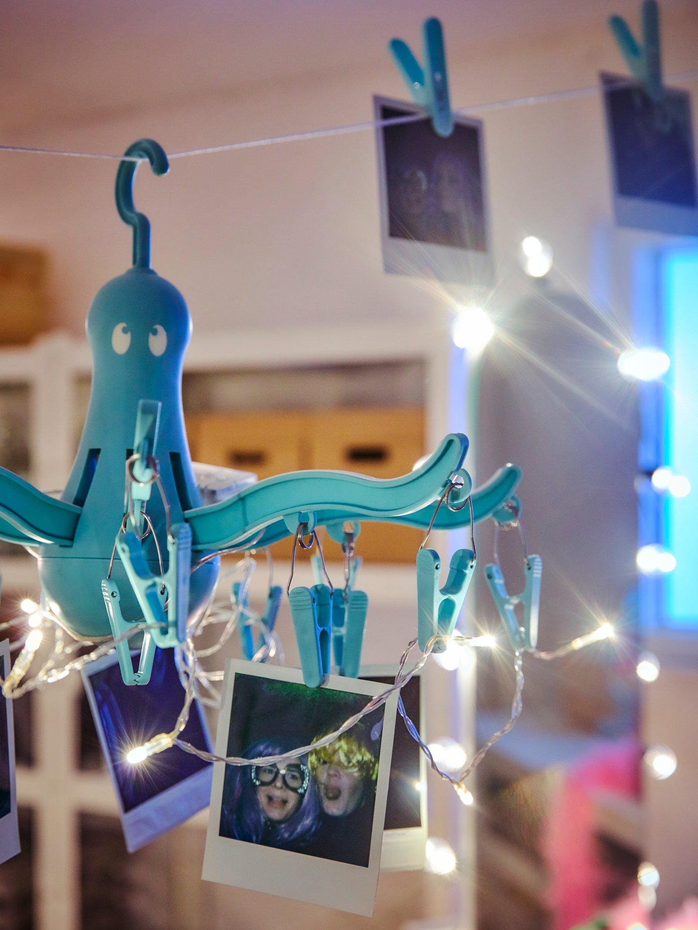 I PRESSA tørrestativ hænger der billeder og lyskæder. 