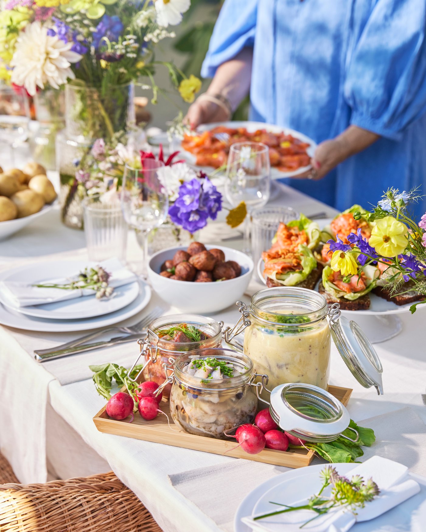 Un dettaglio di una tavolata a festa con il servizio IKEA 360+ e diversi fiori di campo. 