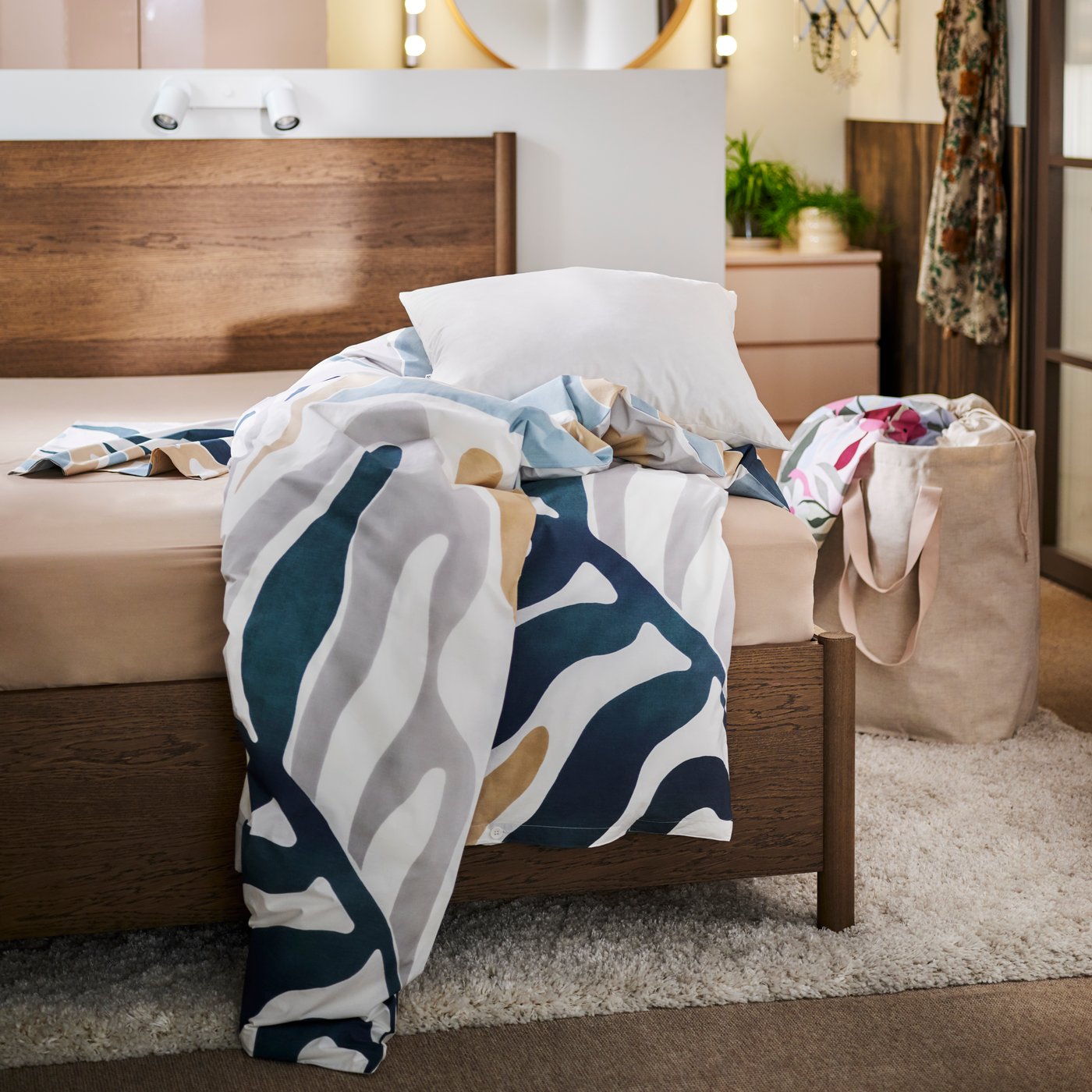 A brown stained oak veneer TONSTAD bed with a grey-beige sheet and duvet covered in MYGGLASVINGE bed linen.