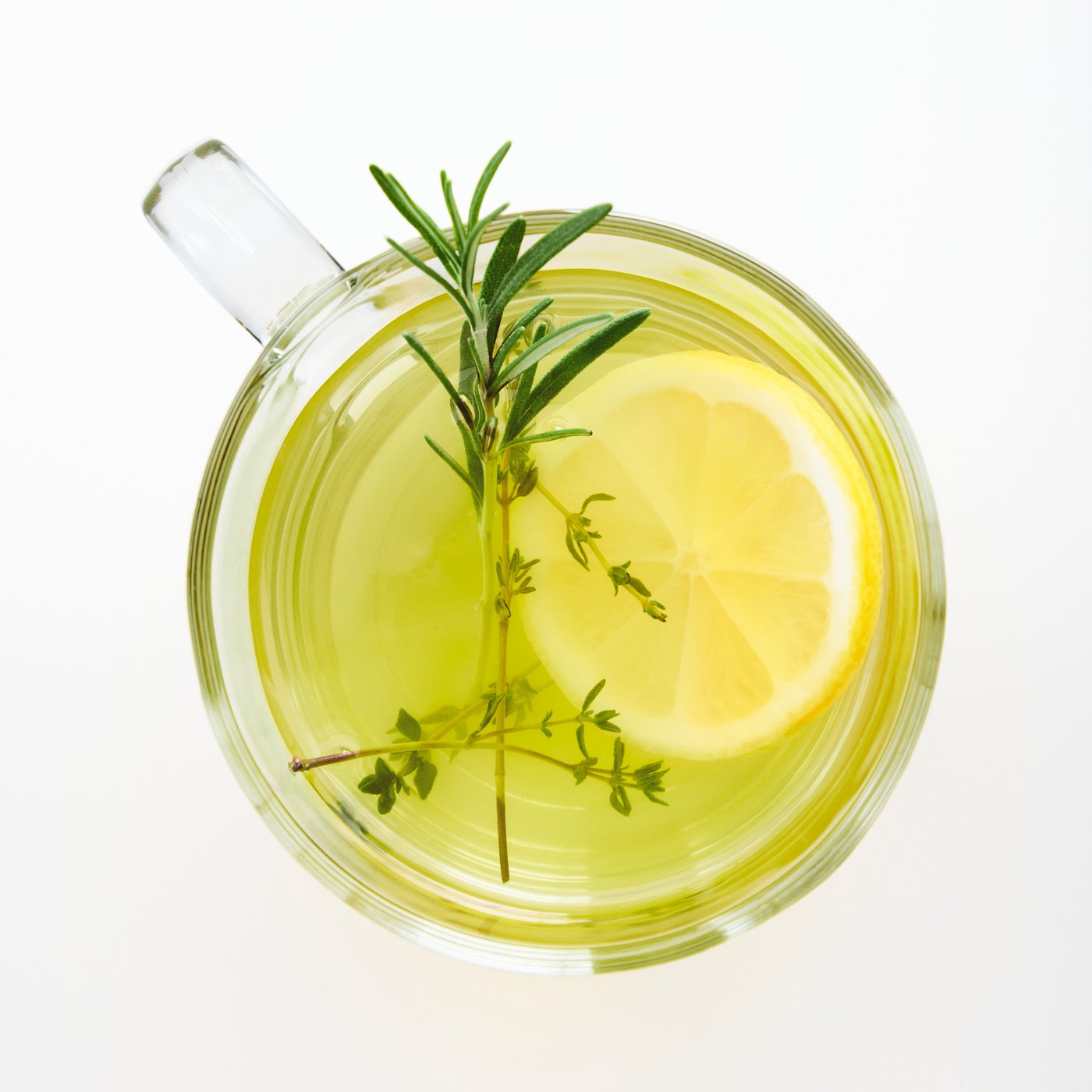Close-up of an IKEA 365+ mug in clear glass, seen from above. Inside we see green tea, rosemary, and lemon.