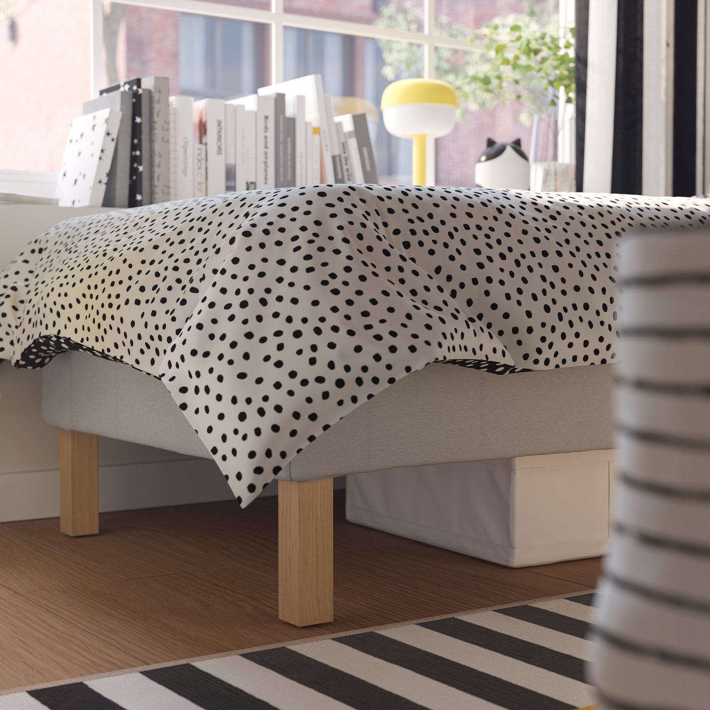 A BLÅSVERK table lamp stands near a pocket spring mattress base with 20 cm BURFJORD legs and BJÖRKGRÅMAL bed linen.