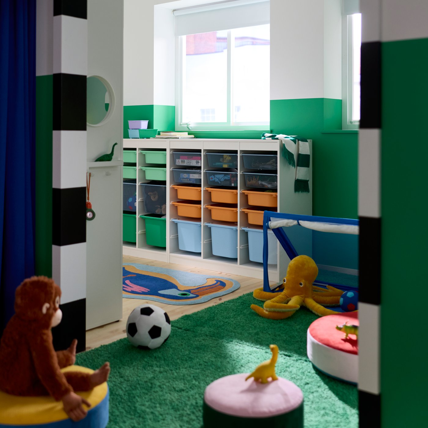 A children’s bedroom with walls painted green and white and a TROFAST system with boxes in different sizes and colours.