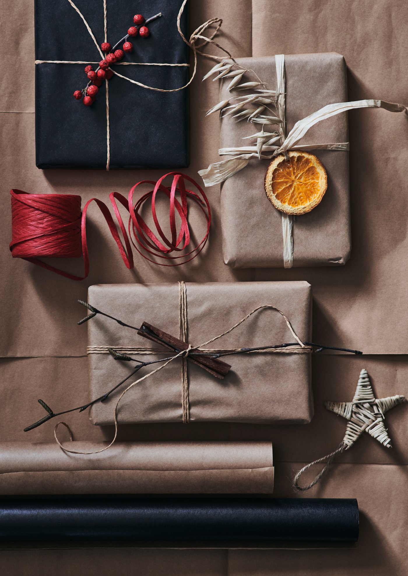 Paket inslagna i svart och brunt papper dekorerade med rönnbär och kanelstång.