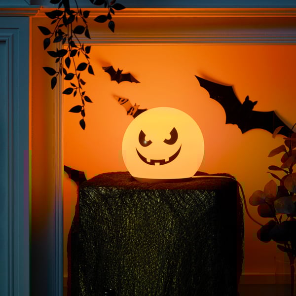 KUSTFYR LED pumpkin light sitting on small round table.