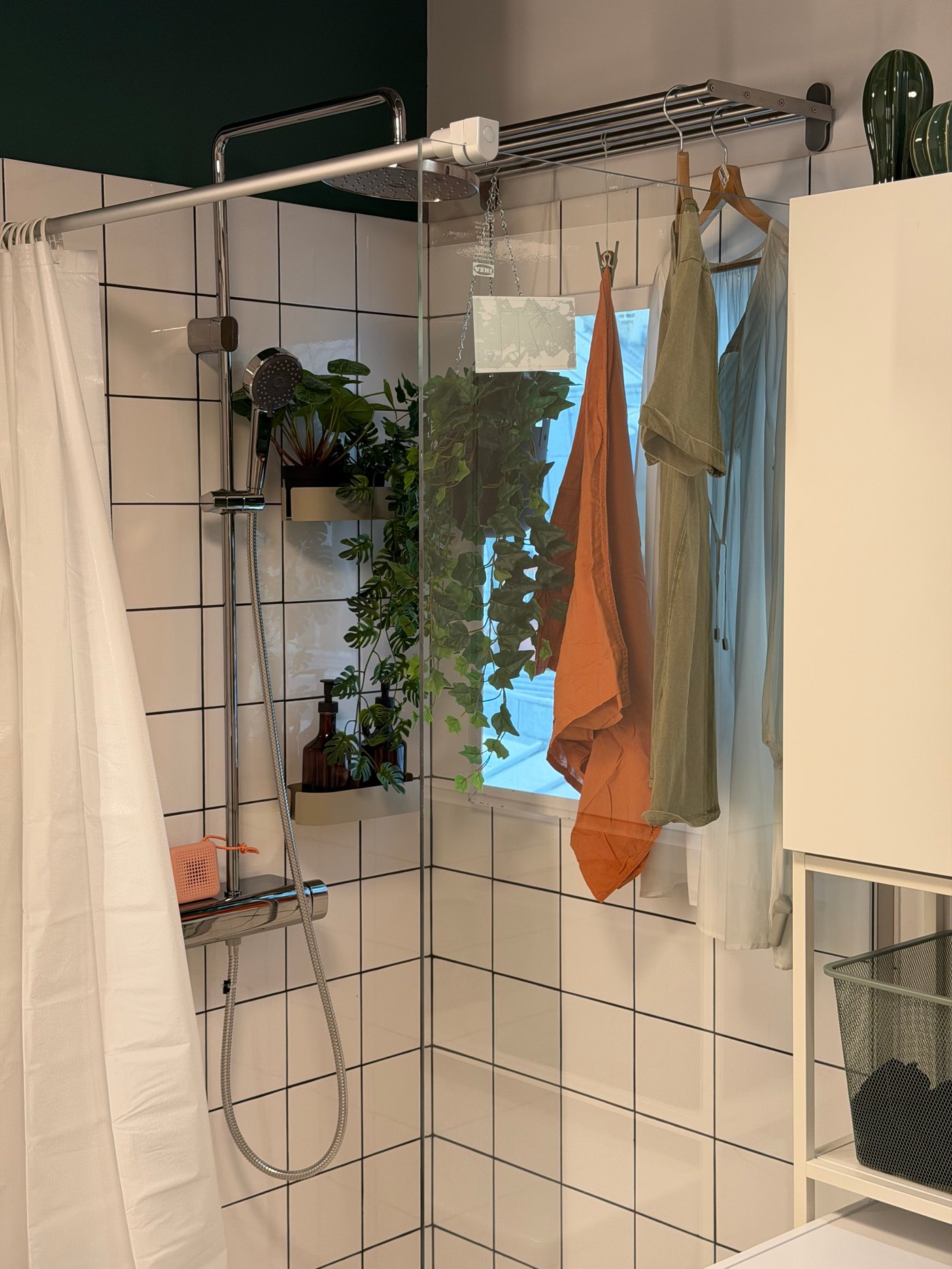 Une salle de bain blanche avec du linge qui sèche dans la douche