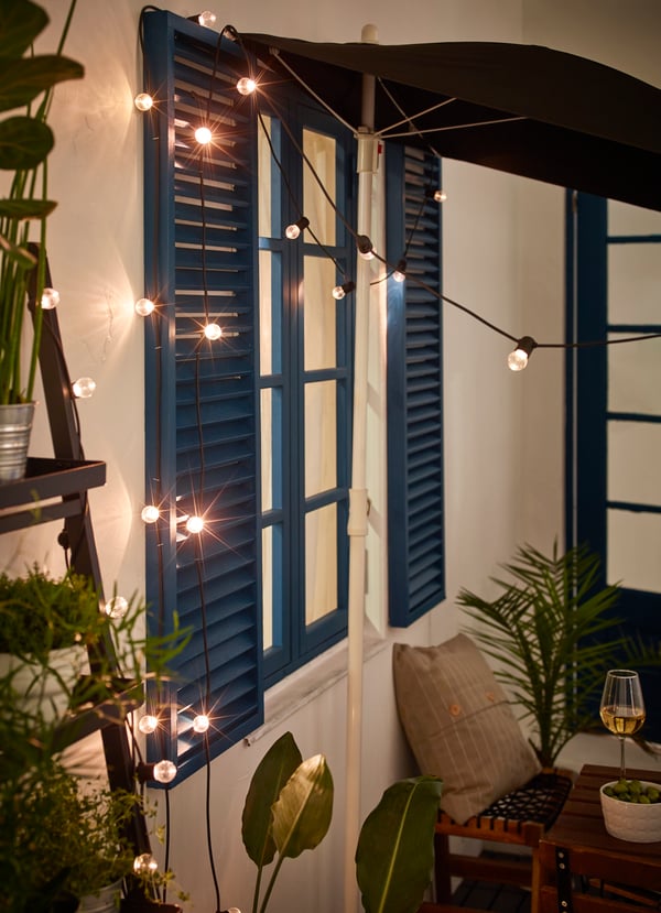 Un patio de una casa con plantas y guirnaldas LED colgando.