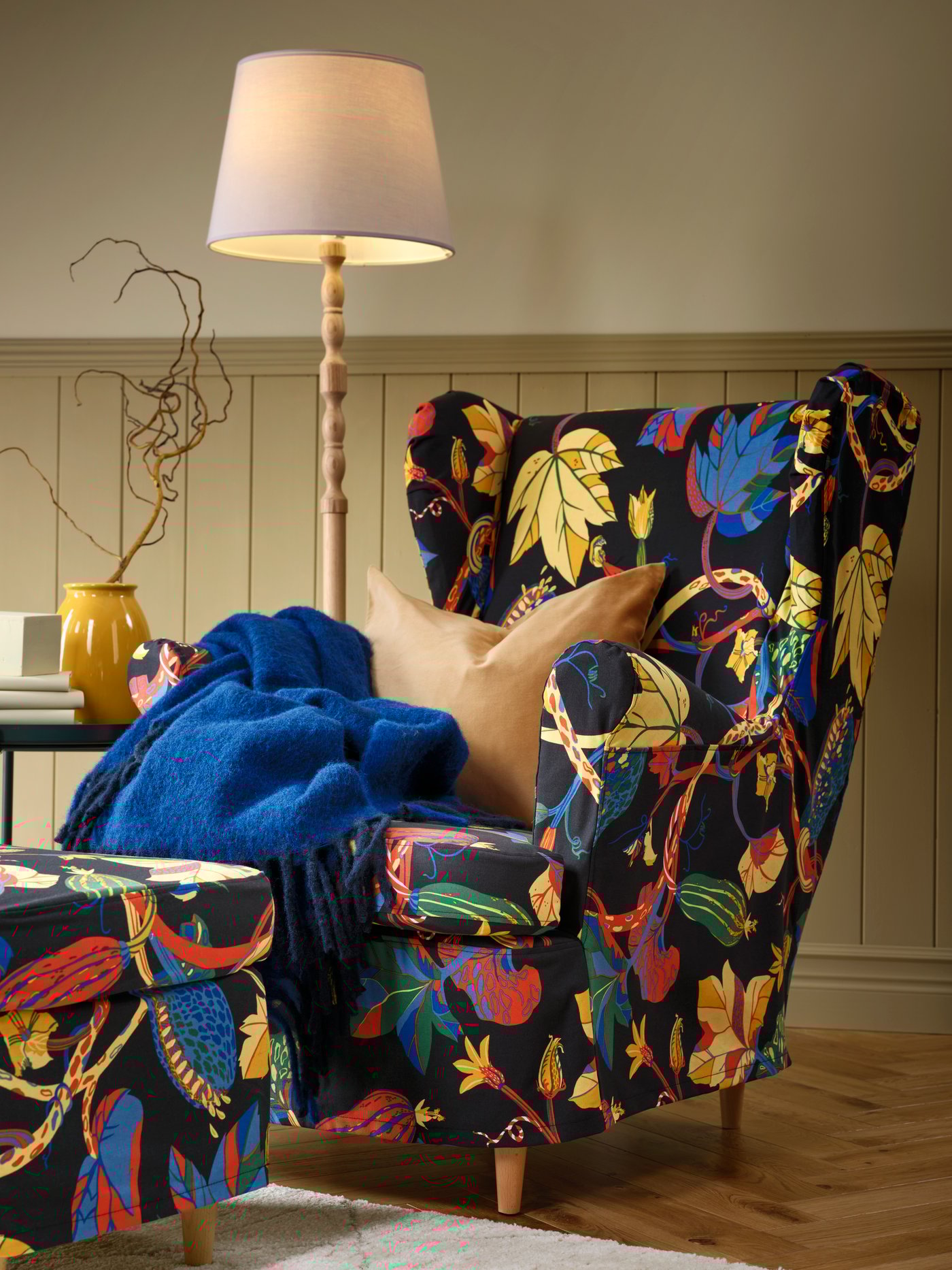 En KINNAHULT gulvlampe i ask og hvitt lyser opp et hjørne i stua.