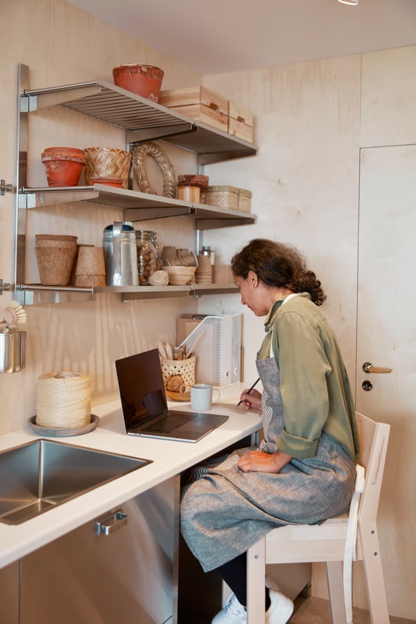 Personne travaillant sur ordinateur sur le plan de travail de sa cuisine