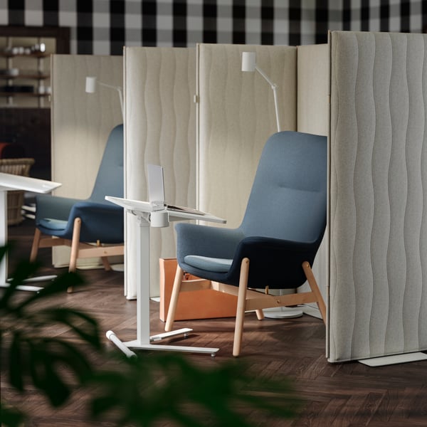 A focus corner with two blue VEDBO armchairs, MITTZON acoustic screens around them, and MITTZON laptop tables in front.