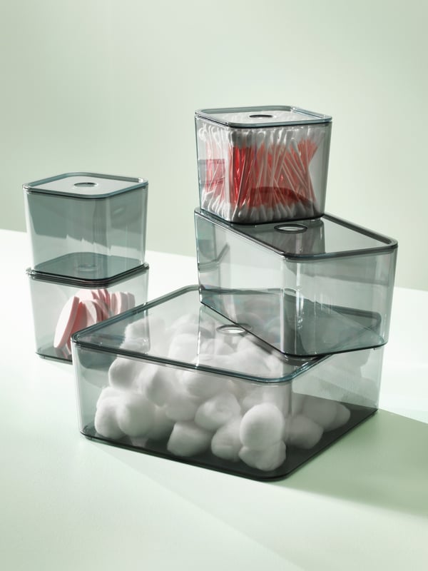 VISSLAÅN boxes, in different sizes, are stacked in a light green space. One contains cotton buds and one contains cotton balls.