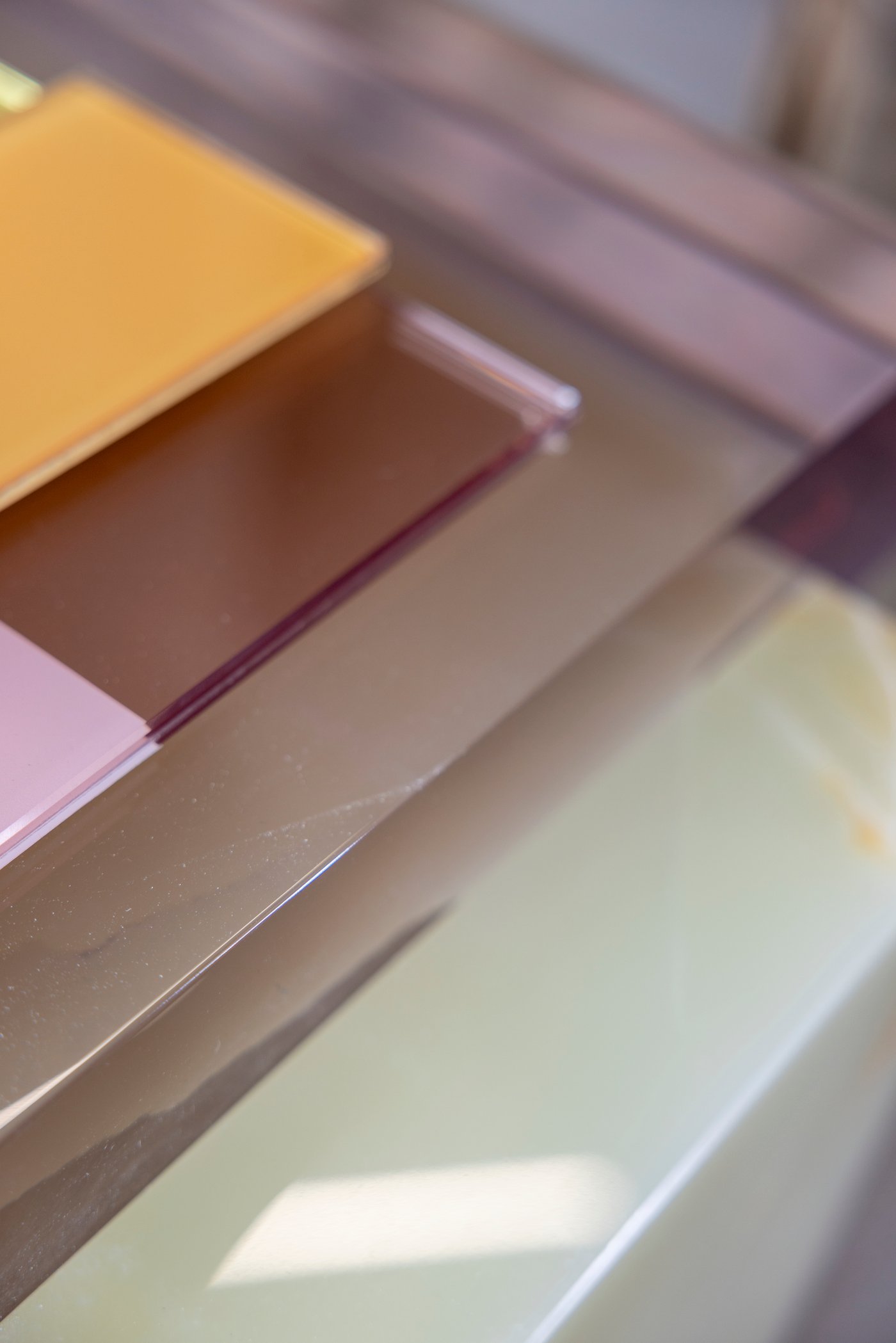 Different sheets of coloured glass are stacked on top of each other.