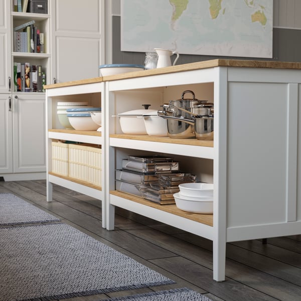 A large kitchen island is used for baking on top and holds lots of cookbooks on the shelves below.