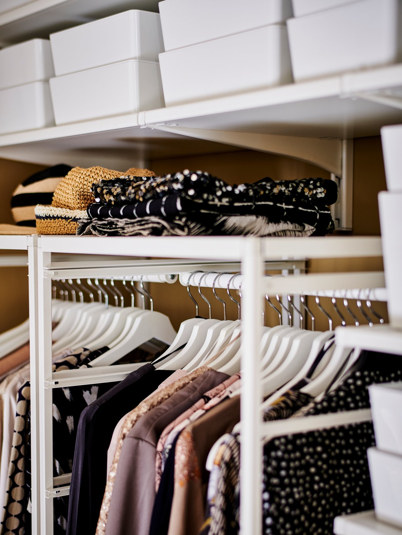 Närbild på klädhängare och lådor i en öppen garderob.