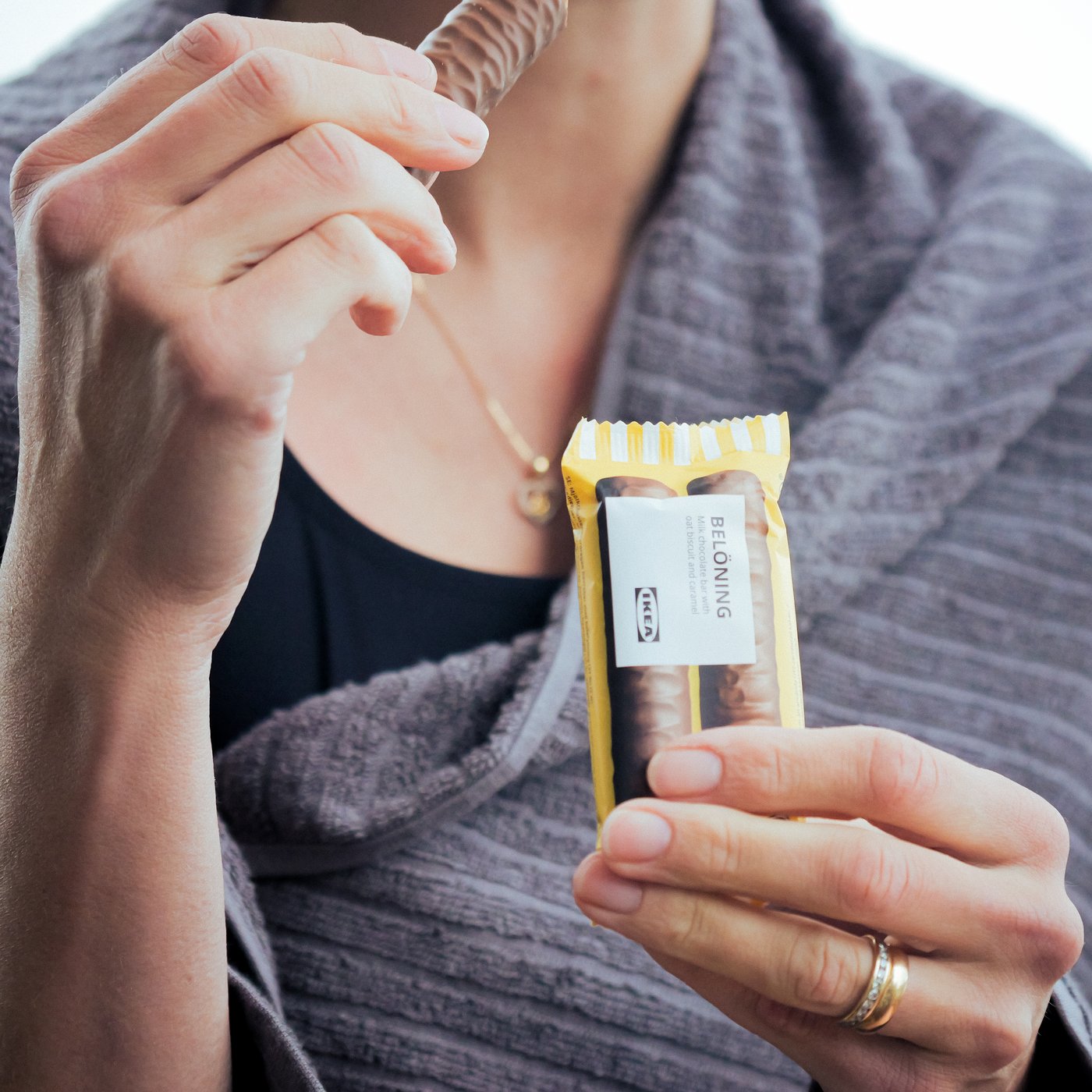 אישה נהנית מחטיף שוקולד BELÖNING כשהיא עטופה במגבת לאחר שחייה.