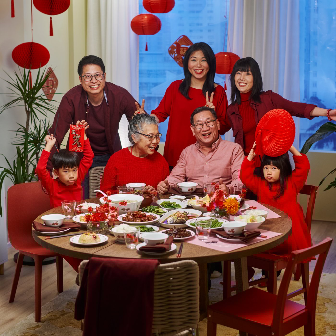A festive dining setting featuring a round table with traditional dishes served in FÖSSTA bowls, surrounded by people.