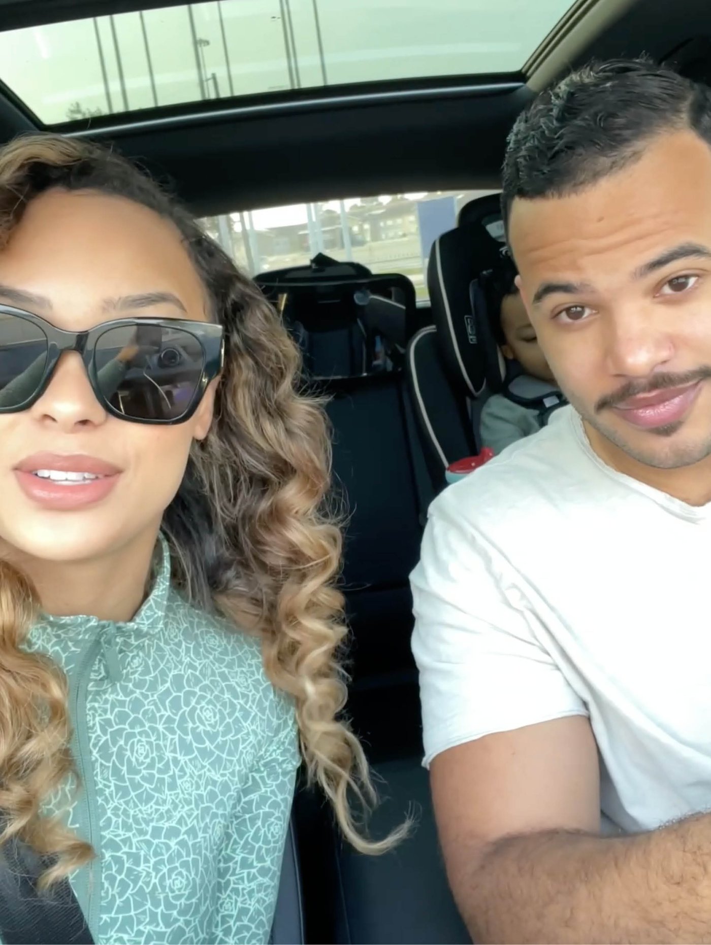 Žena i muškarac sede u automobilu, a dete je u dečjem sedištu koje se nazire u pozadini.