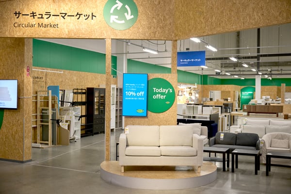 Circular market area in a furniture store with white, black, and gray sofas, shelves and tables in the background.