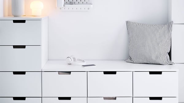 Vit låg hallbyrå med sittbänk. På sittbänken ligger en svart och vit randig kudde.