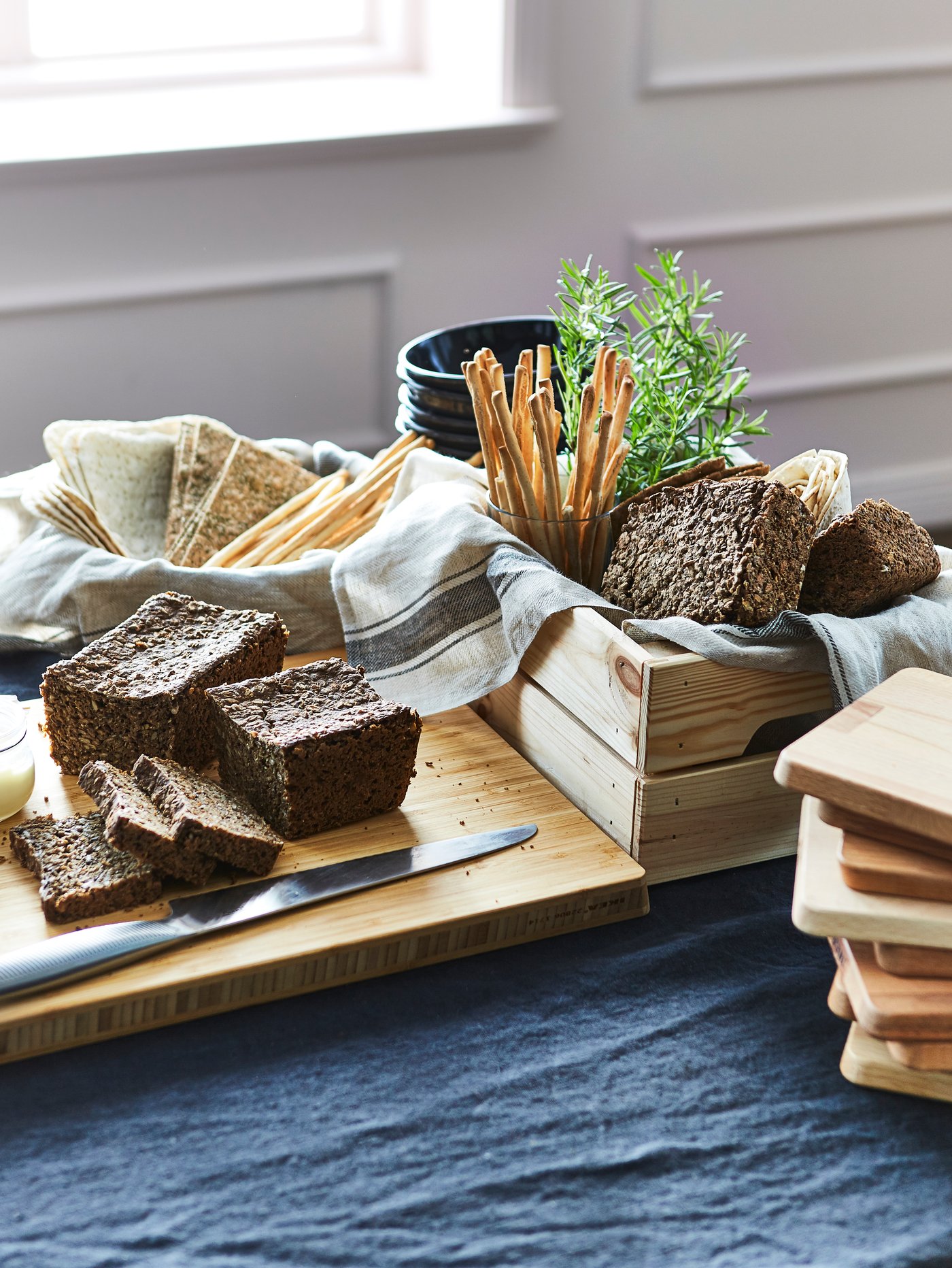 Modern dining room close-up of a beige butchers block made out of bamboo, next to a rectangular box and multiple bowls.