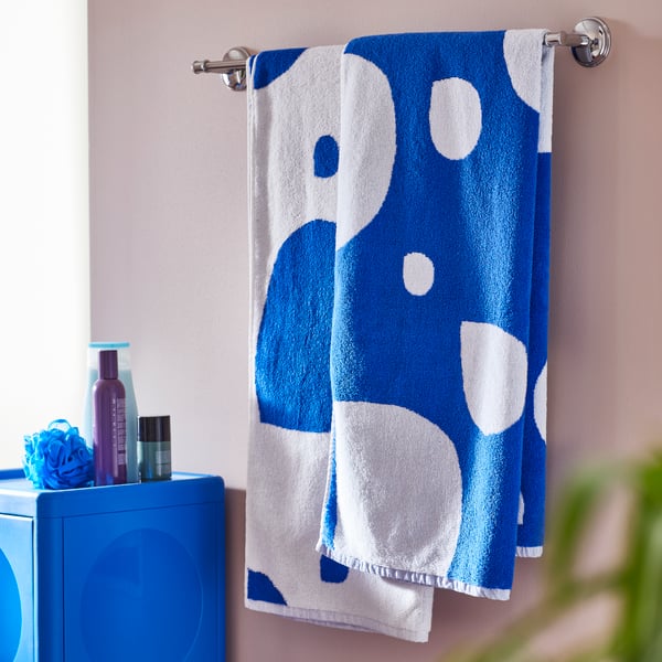 Two blue and white BERGVATTNET bath towels are hanging on a chrome-plated BALUNGEN towel rail on a bathroom wall.