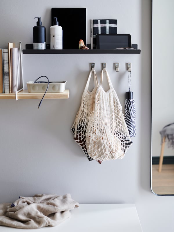 Two cotton and hemp NEREBY containers holding cutlery and tea towels hang off a storage rail in a kitchen setting.