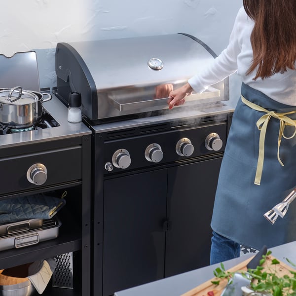 Person som grillar vid en gasolgrill i ett rejält utekök. 