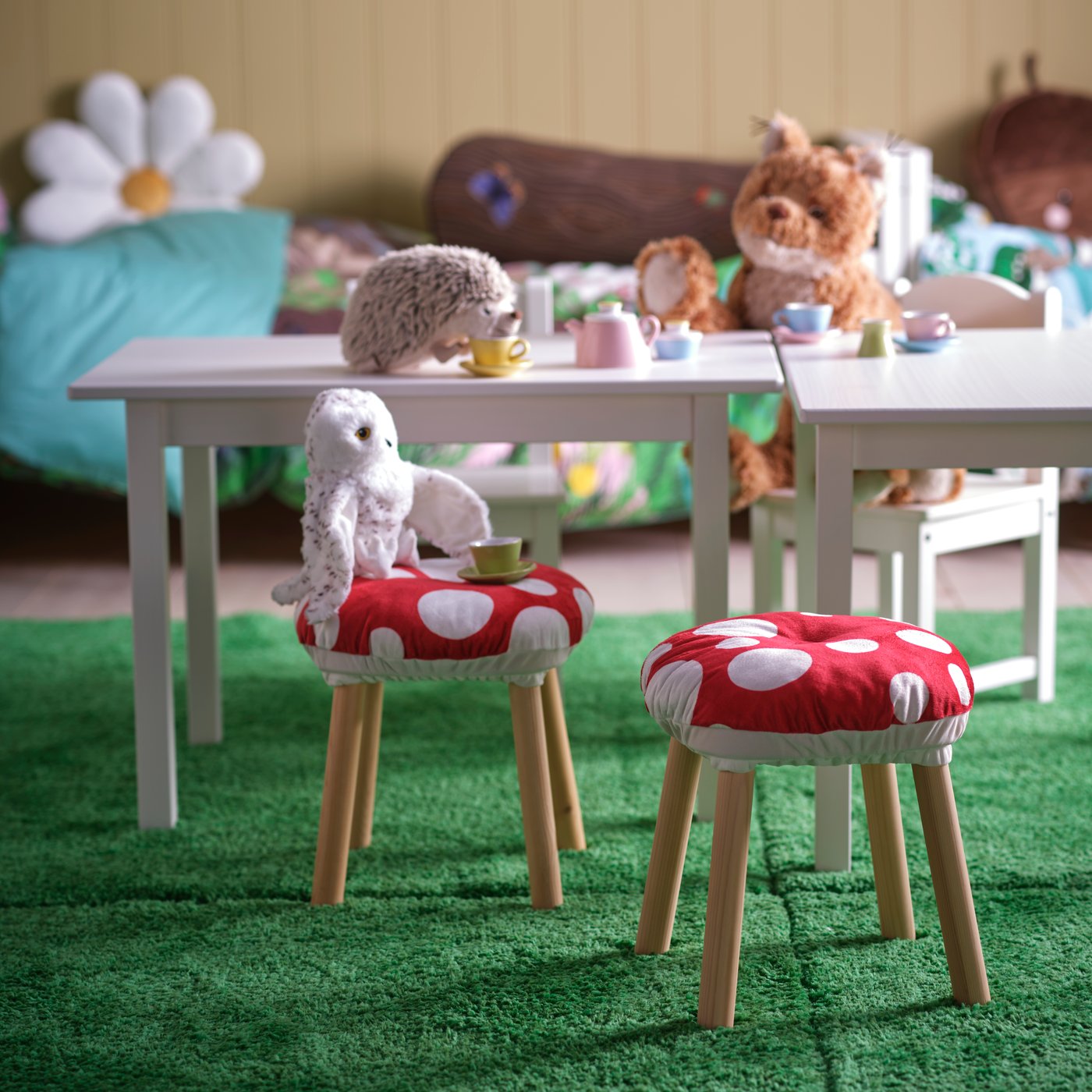 Um quarto de criança com diferentes peluches SKOGSDUVA a fazer um chá de brincar e bancos com capas SKOGSDUVA.