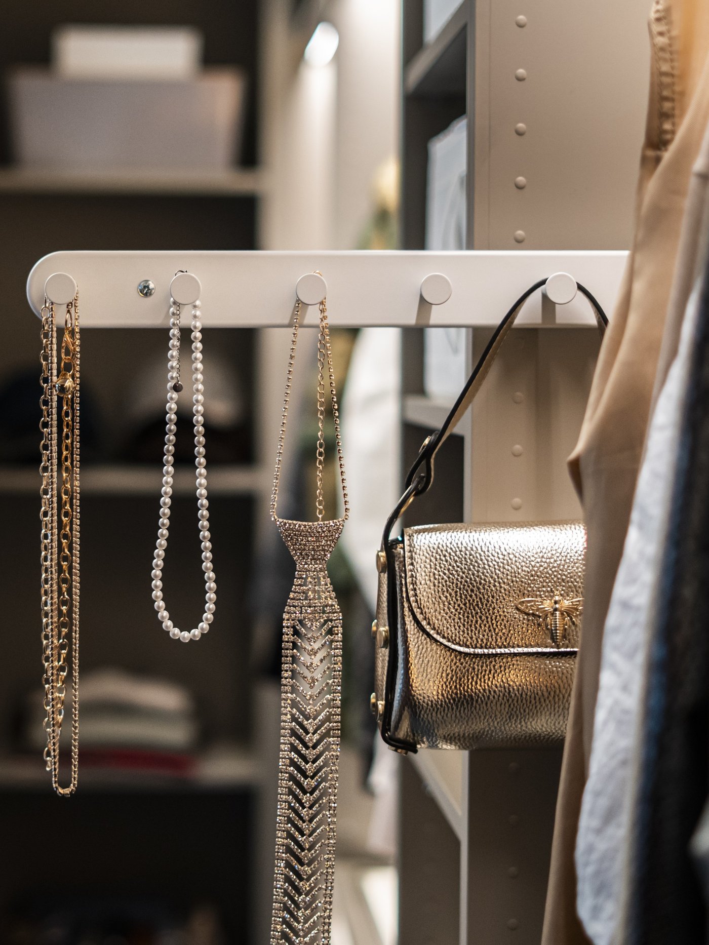 Appendiabiti estraibile bianco KOMPLEMENT montato nell’armadio, usato per organizzare cinture, collane e una borsa.