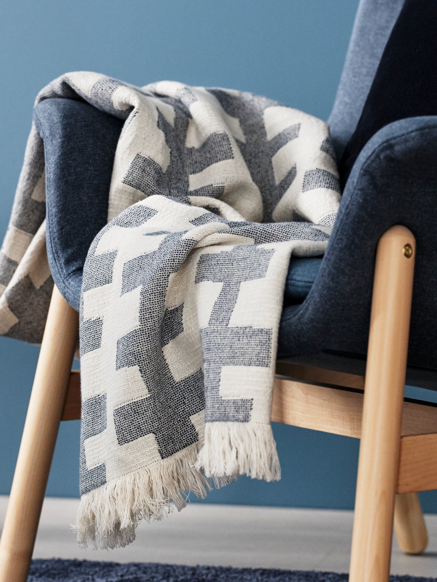 Biała poduszka VATTENMÅRA na białej kanapie. Poszewka na poduszkę ze wzorem różowych roślin.