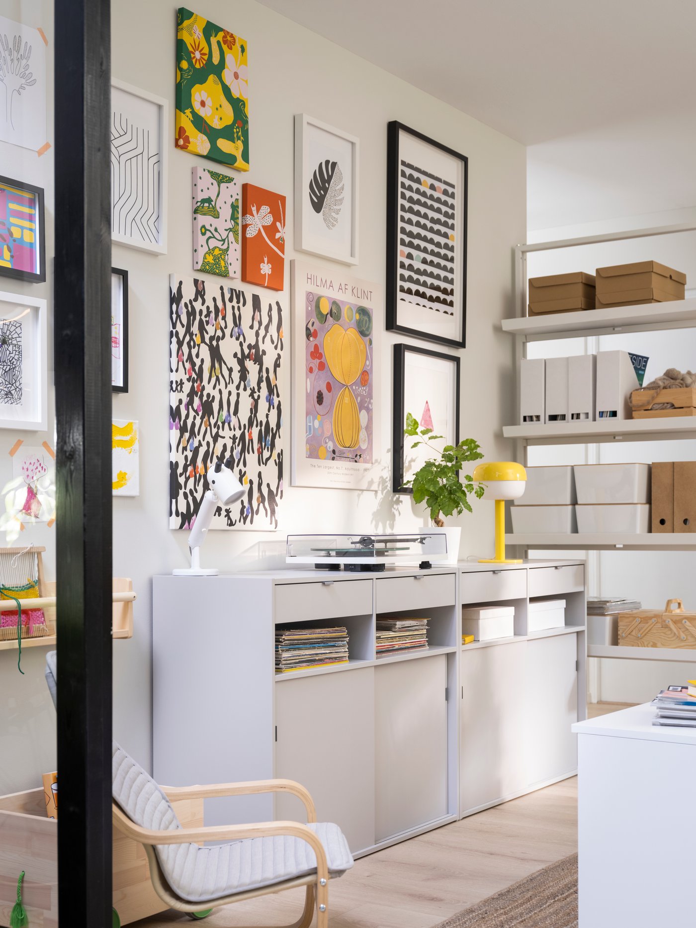 An office space with a SPIKSMED sideboard with frames above. There is also a children's armchair and a display shelf next to it.