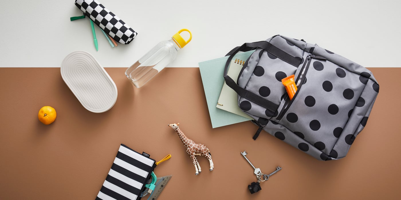 Una mochila STARTTID junto a una botella de agua FORMSKÖN y un recipiente para comida HALVVARM, una bolsa de accesorios SKÖRDA y otros artículos.