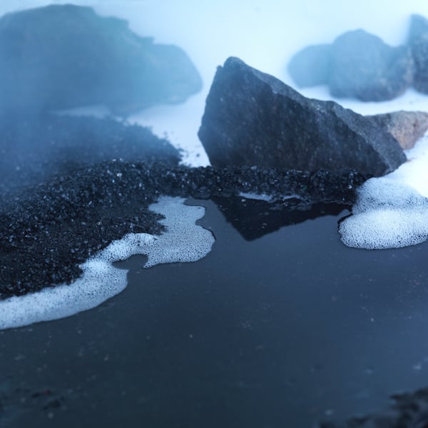 Close-up of black rocks and gravel in water.