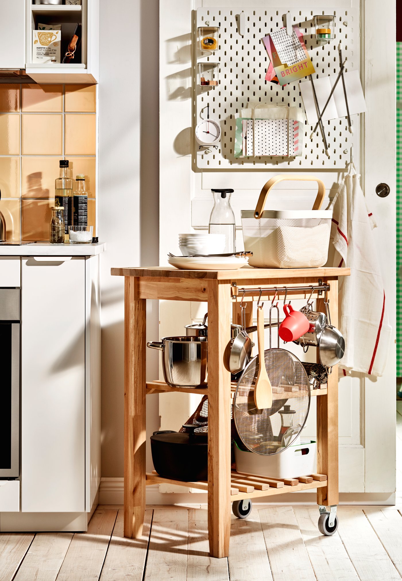 Ein BEKVÄM Servierwagen aus Holz mit Töpfen, Pfannen und anderen Utensilien als Verlängerung der Arbeitsfläche.