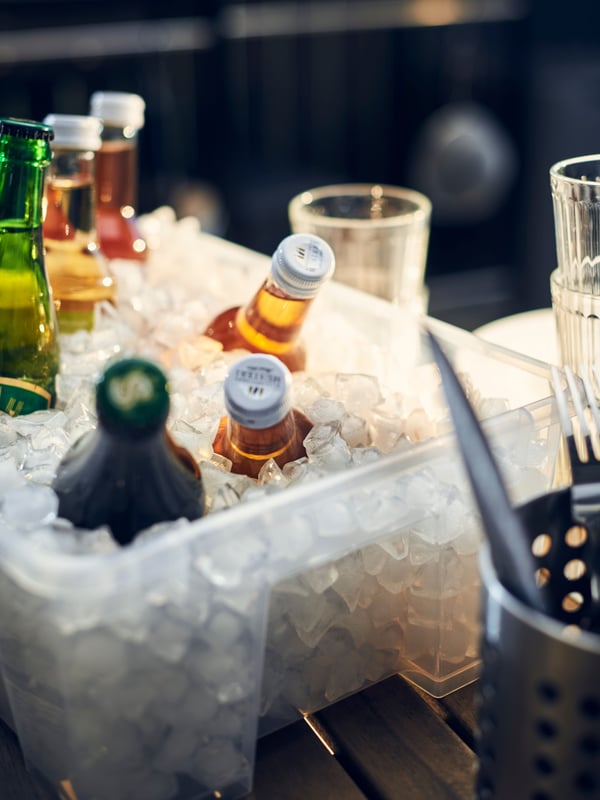 A SAMLA bucket of ice holds various beverages at an outdoor event.