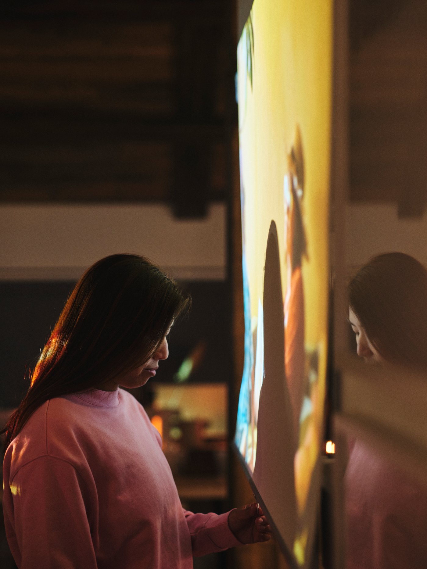 Personne debout devant un store à enrouleur opaque TRETUR blanc abaissé sur lequel est projeté un film.