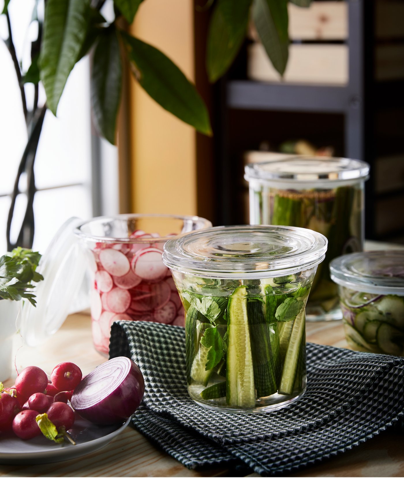 Sur une table se trouvent plusieurs bocaux en verre remplis de divers légumes et une assiette remplie d’autres légumes.