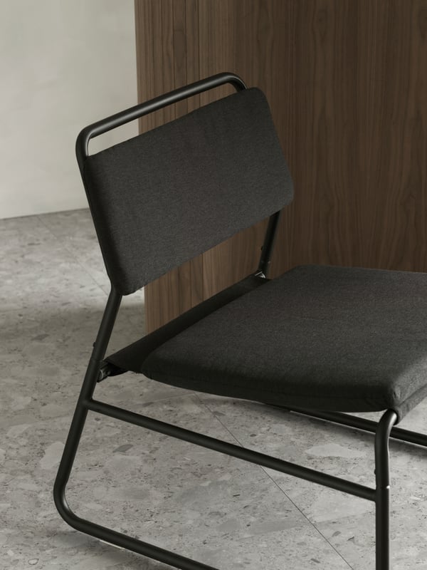 A close-up of the dark grey LINNEBÄCK easy chair with an airy design made with a metal frame and upholstered seat and back.