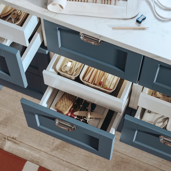 Drawers in a kitchen island with fronts in LERHYTTAN blue and with chrome-plated ENERYDA handles have been pulled out.